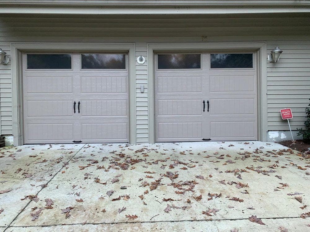 Carriage-style double garage doors in tan finish with decorative hardware